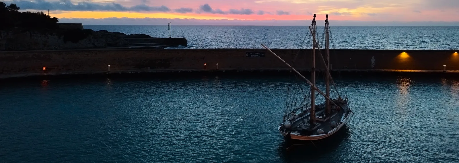 Il porto di Tricase al tramonto, con una barca a vela d'epoca
