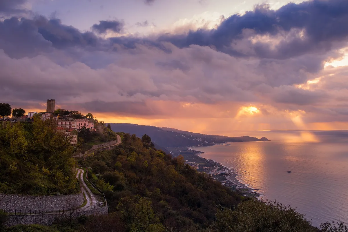 Piraino al tramonto, con la torre sul crinale e la costa tirrenica che si apre sul mare